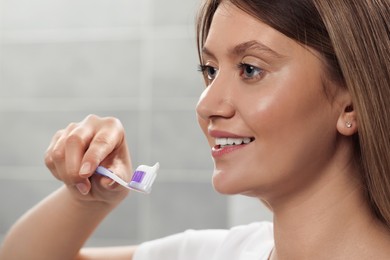 Photo of YOUNG Woman holding brush with toothpaste in bathroom