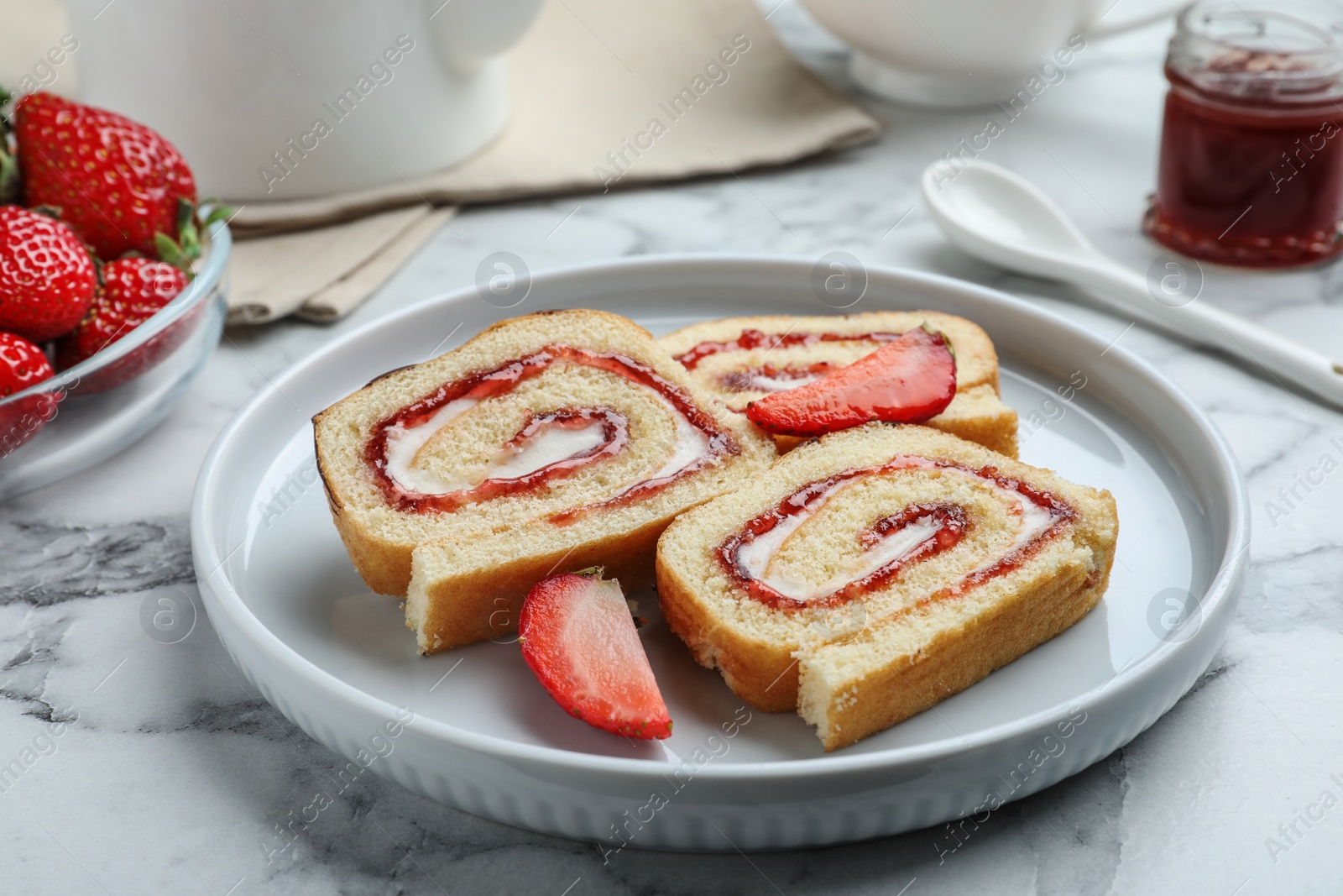 Photo of Tasty cake roll with strawberry jam and cream on white marble table