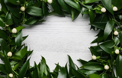 Beautiful handmade mistletoe wreath on white wooden table. Space for text