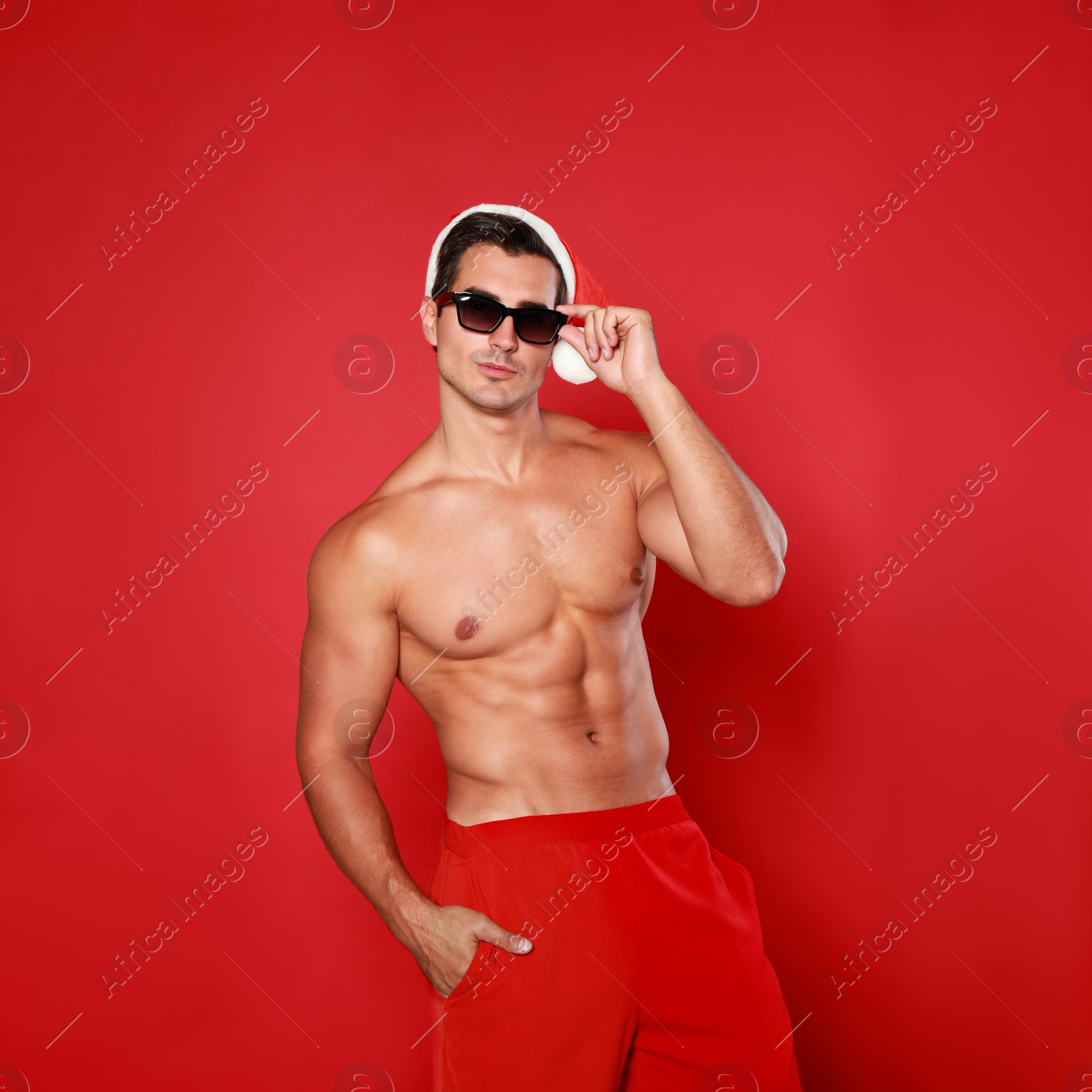 Photo of Sexy shirtless Santa Claus on red background