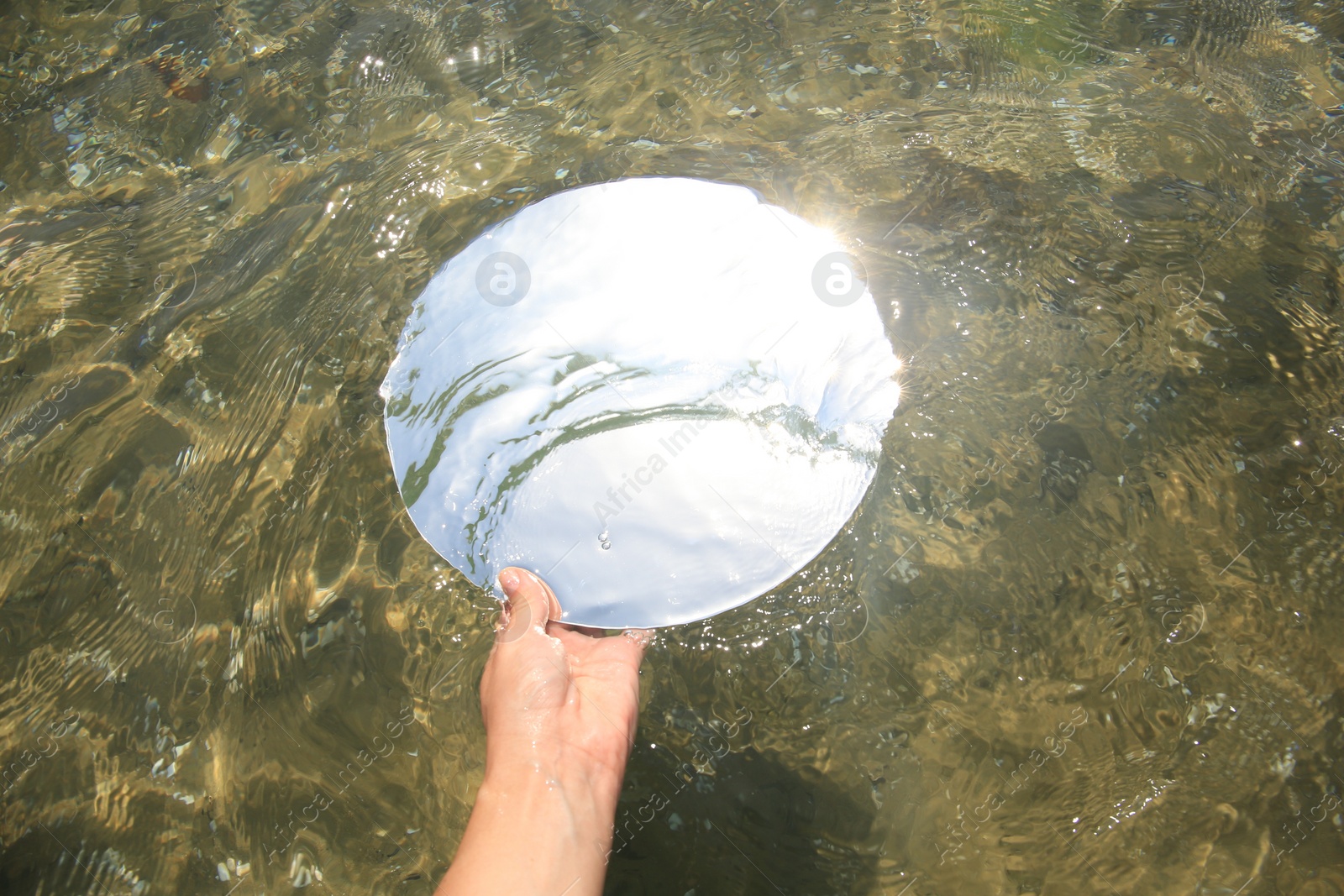 Photo of Woman immersing round mirror in sea on sunny day, above view