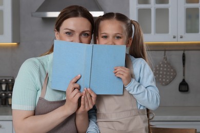 Woman and her daughter with recipe book in kitchen