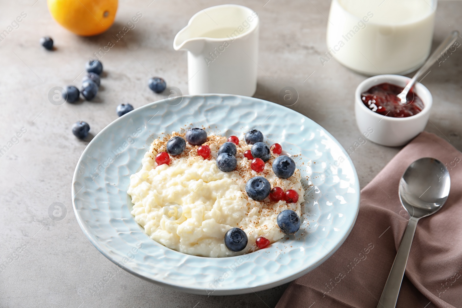 Photo of Creamy rice pudding with red currant and blueberries in bowl served on table