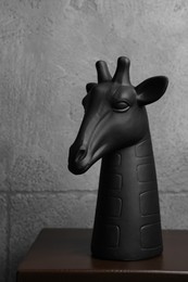 Photo of Wooden shelf with decorative figure of giraffe against grey wall