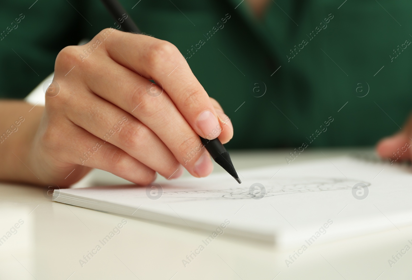 Photo of Woman drawing with pencil in notepad at white table, closeup