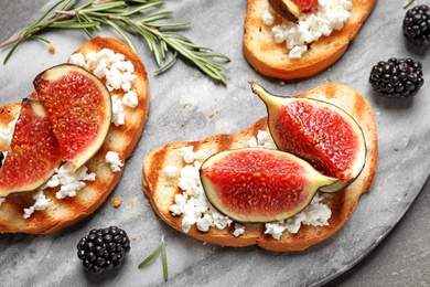 Photo of Bruschettas with ripe figs and cheese served on board, closeup