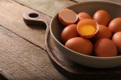 Photo of Bowl with raw chicken eggs on wooden table, closeup. Space for text