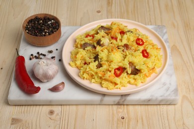 Delicious pilaf with meat and ingredients on wooden table