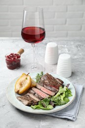 Photo of Delicious roasted beef meat, caramelized pear and greens served on light table