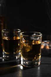 Photo of Alcohol addiction. Whiskey in glasses on black wooden table