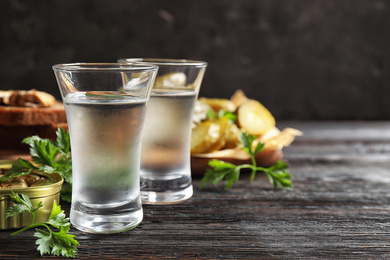 Photo of Cold Russian vodka with snacks on black wooden table, closeup