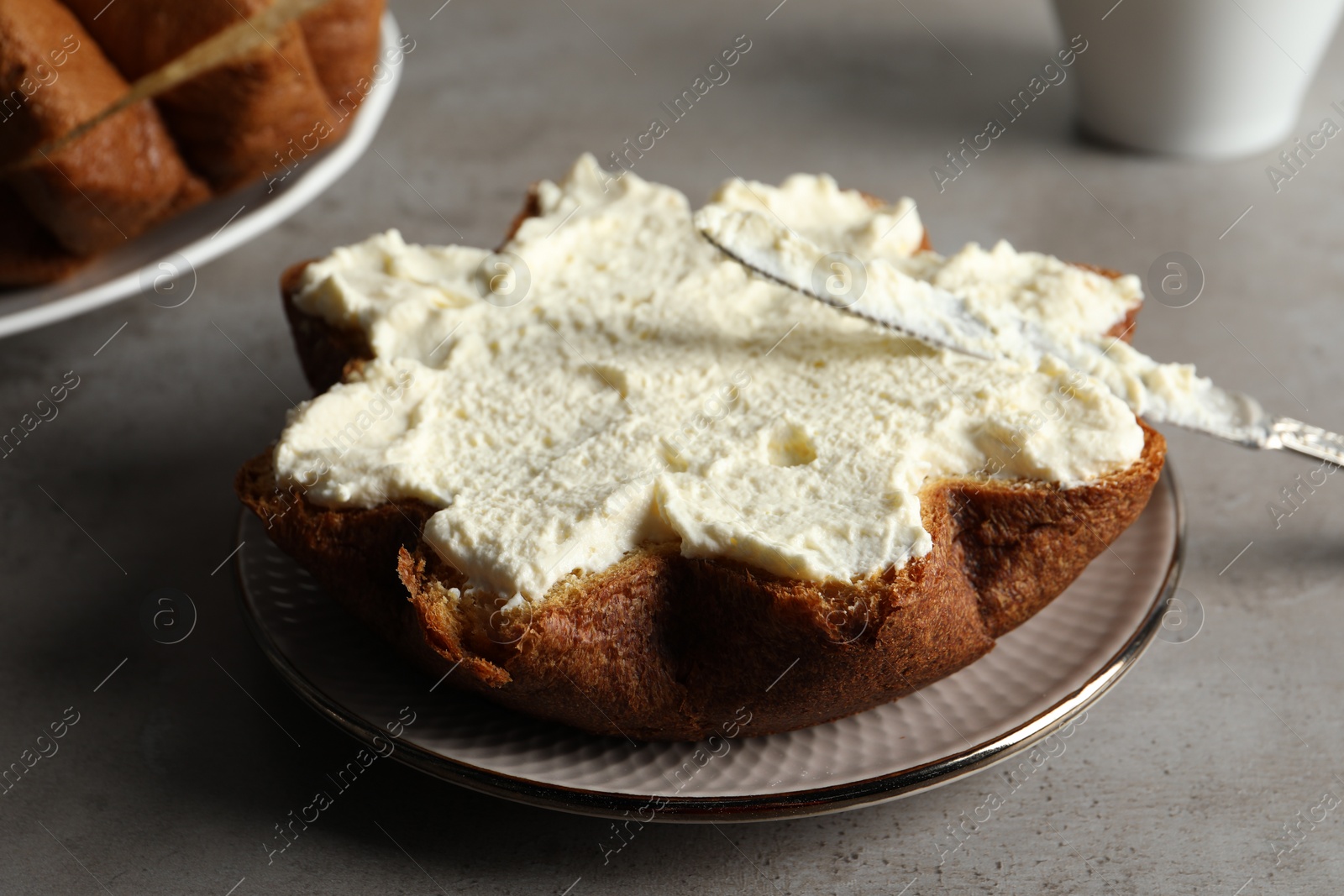 Photo of Slice of delicious Pandoro cake with cream on grey table