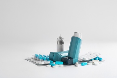 Asthma inhalers and pills on white background