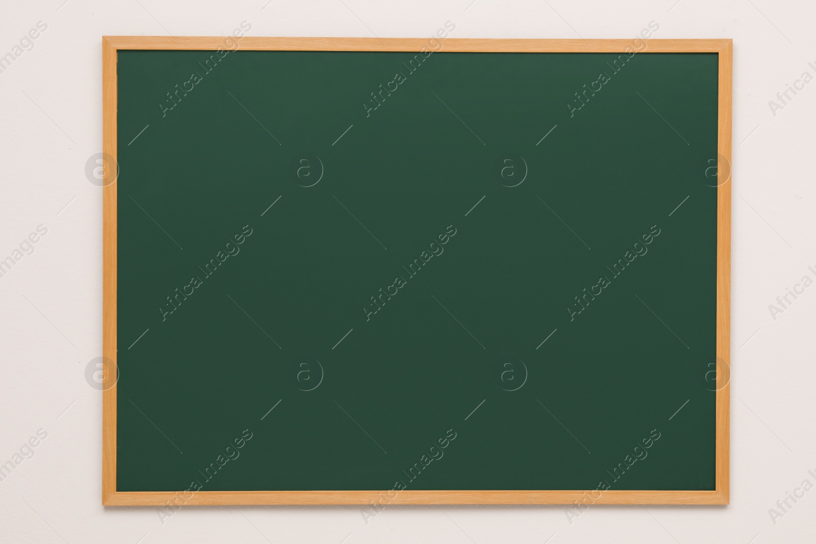 Photo of Clean green chalkboard hanging on grey wall