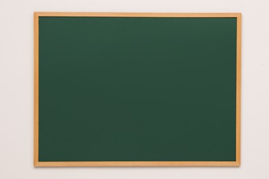 Clean green chalkboard hanging on grey wall