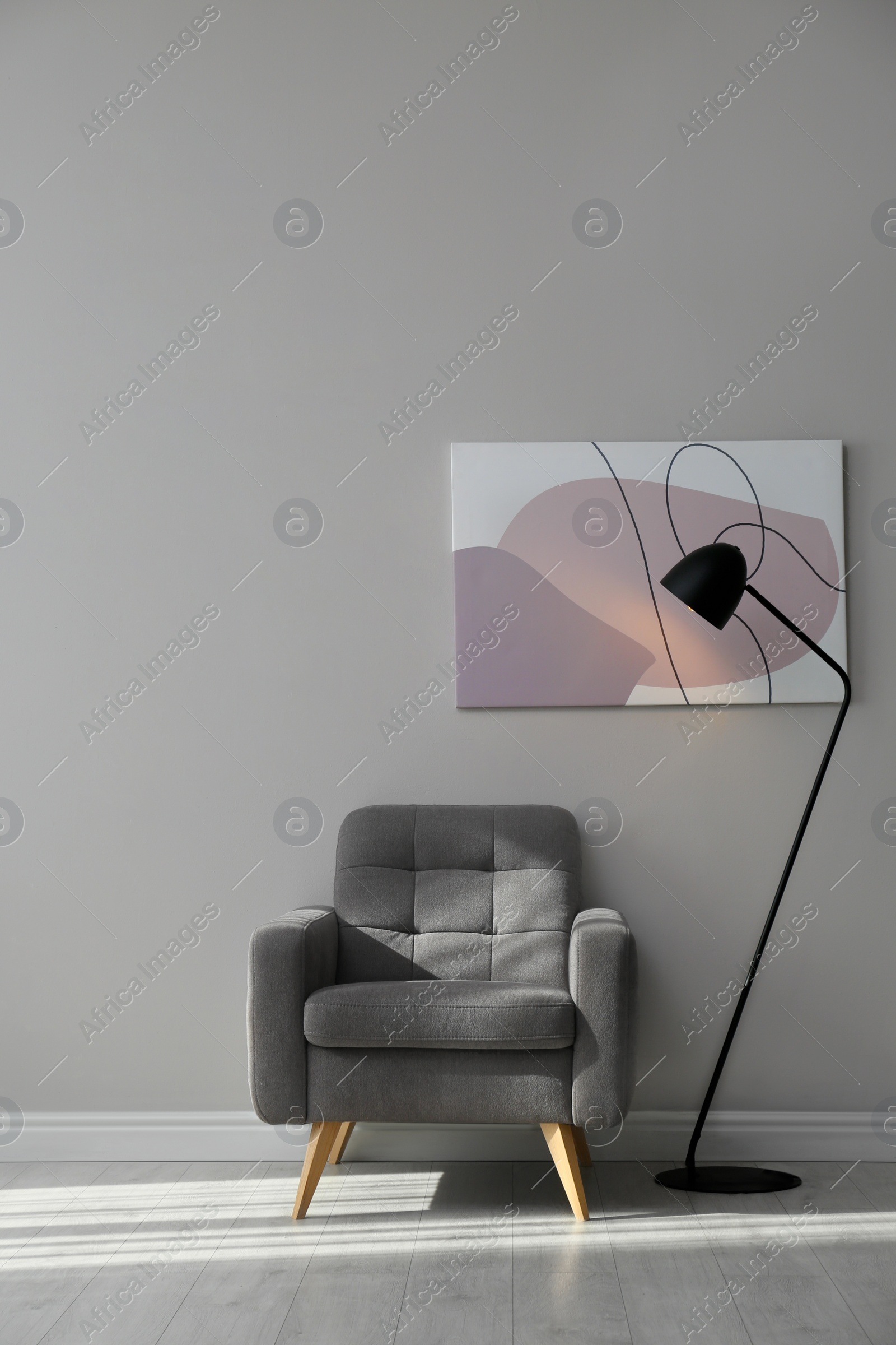 Photo of Stylish armchair and lamp near grey wall with beautiful picture. Interior design