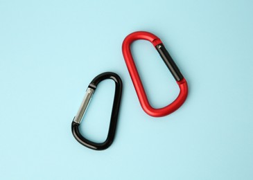 Photo of Two metal carabiners on light blue background, flat lay