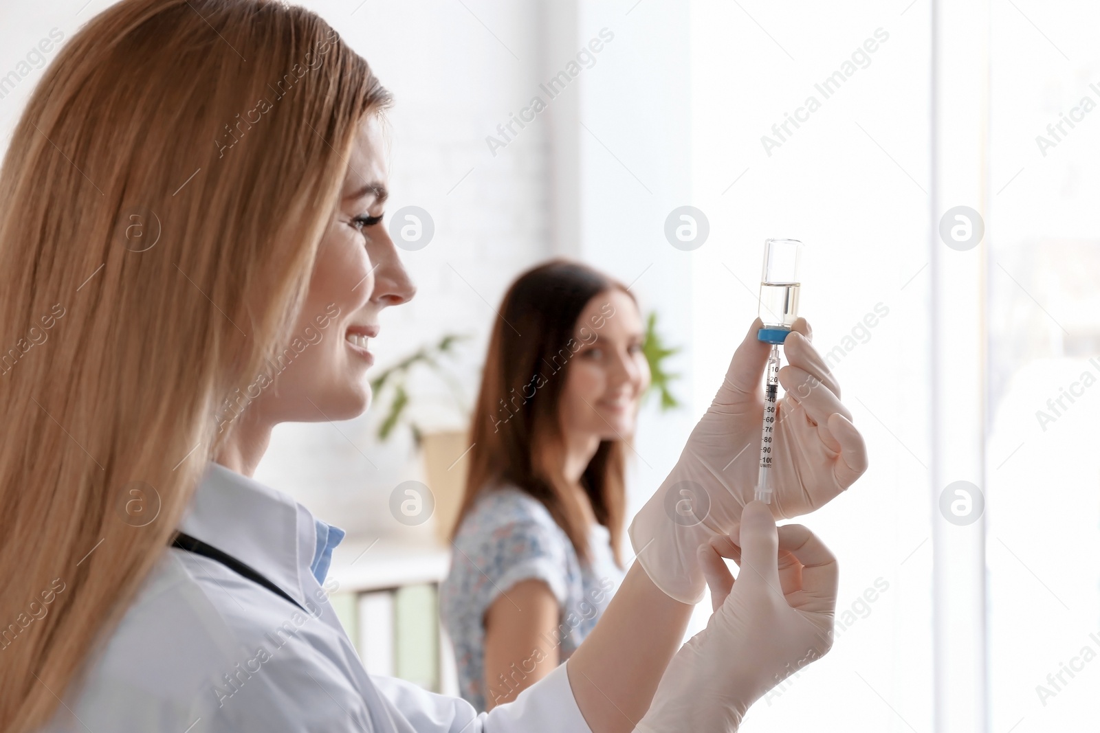 Photo of Doctor holding ampule with vaccine and syringe for patient in clinic