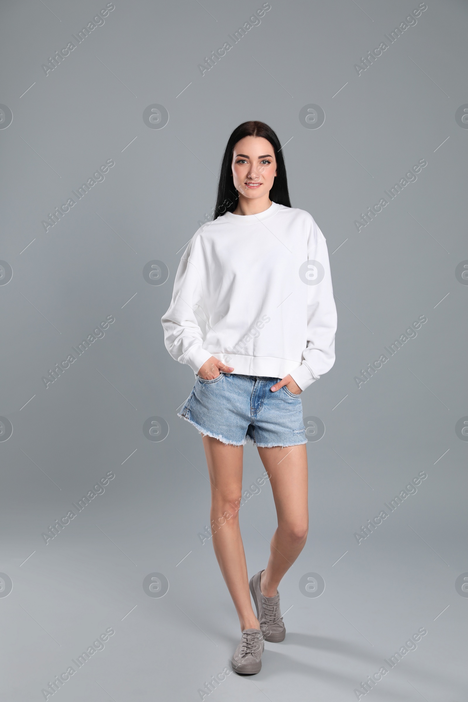 Photo of Full length portrait of young woman in sweater on grey background. Mock up for design