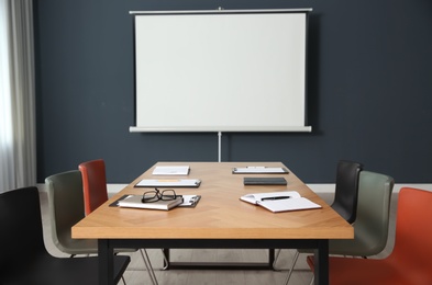 Photo of Modern meeting room interior with large table and projection screen