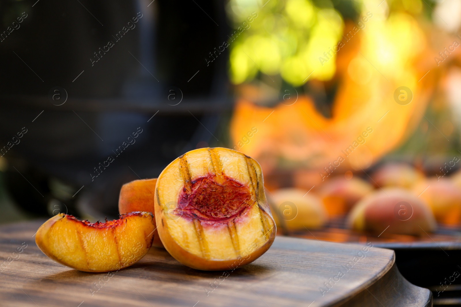 Photo of Cut delicious grilled peach on wooden table outdoors, closeup