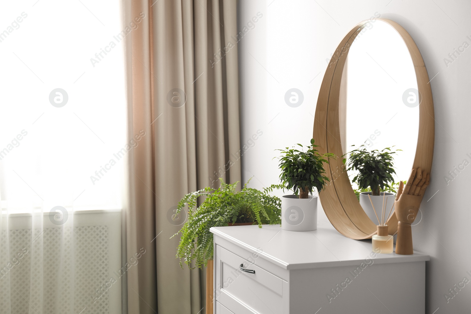 Photo of Round mirror and chest of drawers near white wall in room. Modern interior design