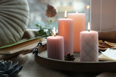 Photo of Tray with burning wax candles and decor on window sill indoors