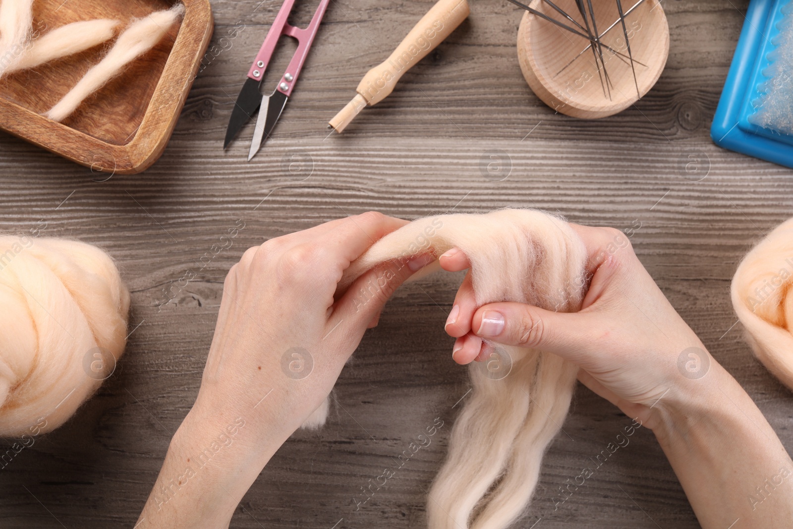 Photo of Woman felting from wool at wooden table, top view