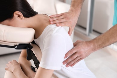 Woman receiving massage in modern chair indoors, closeup