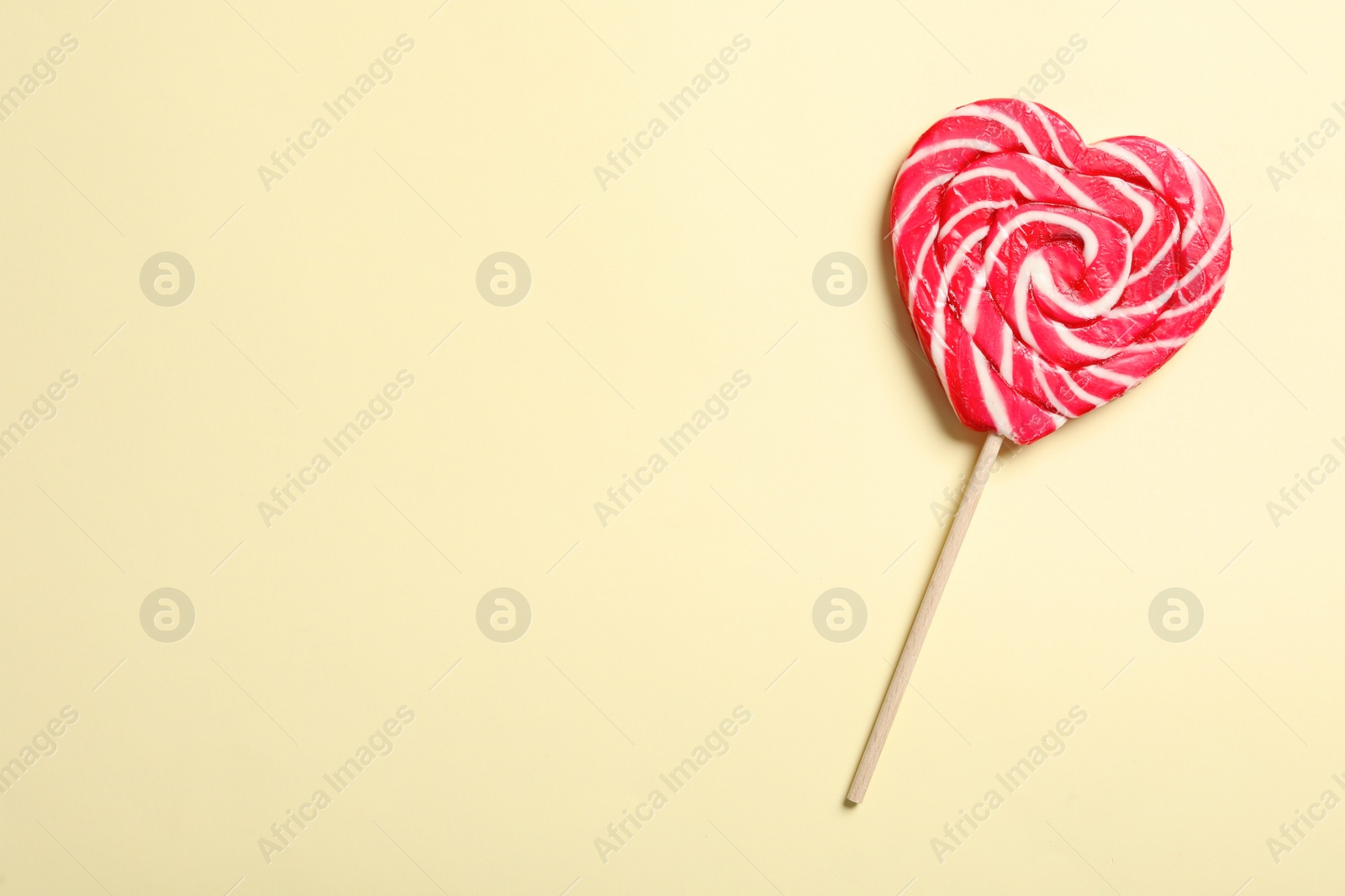 Photo of Sweet heart shaped lollipop on beige background, top view with space for text. Valentine's day celebration