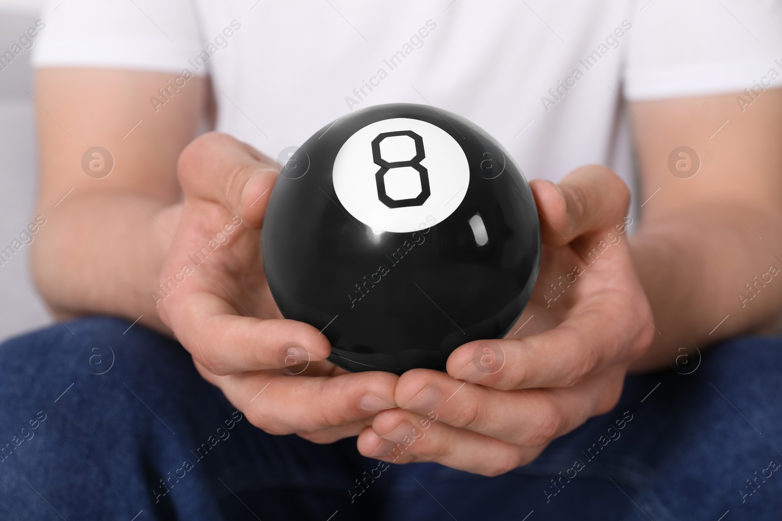 Photo of Man holding magic eight ball indoors, closeup