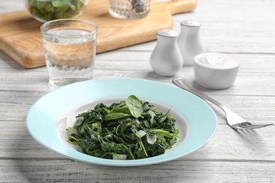 Tasty cooked spinach served on white wooden table. Healthy food