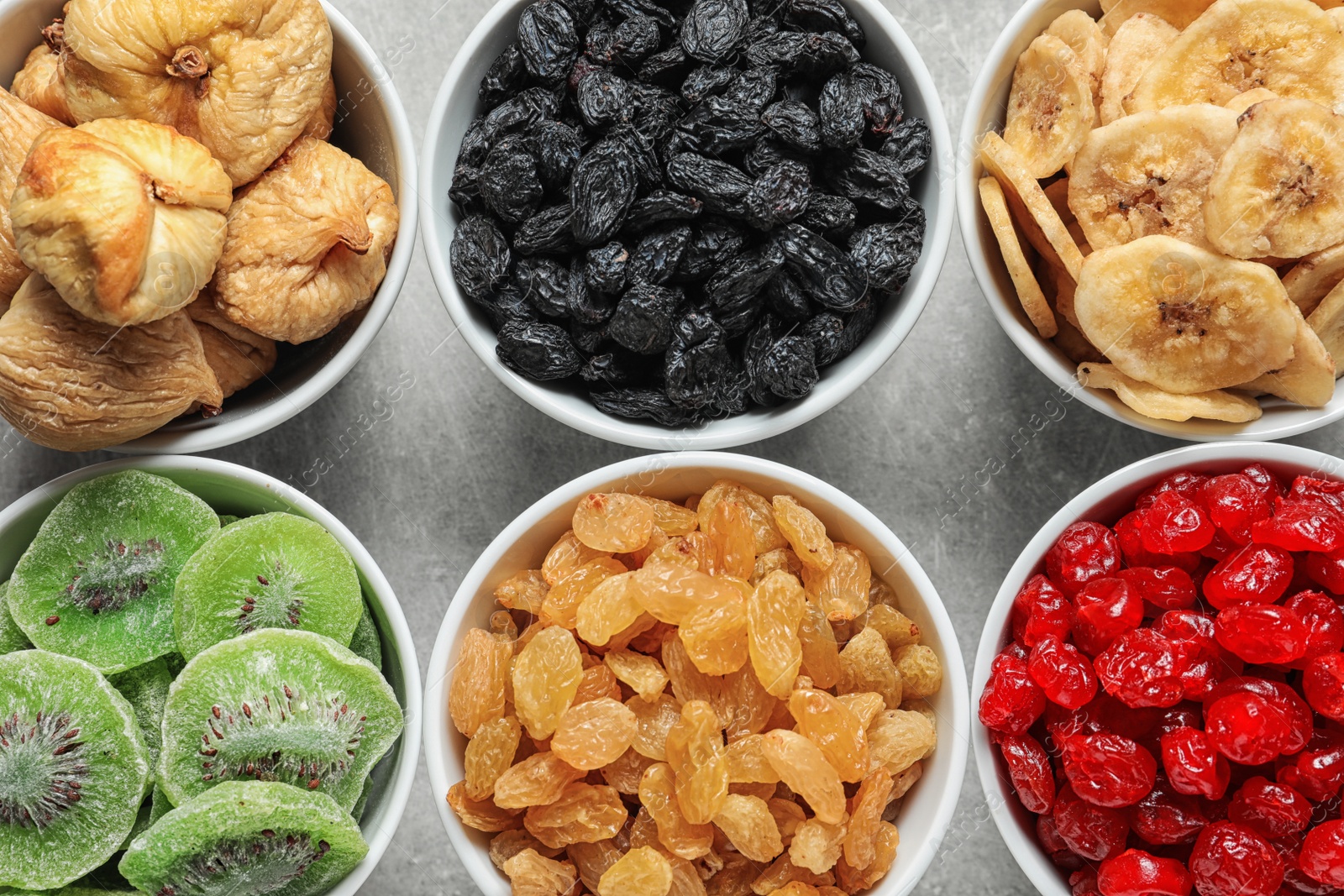 Photo of Bowls with different dried fruits on grey background, flat lay. Healthy food