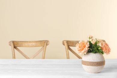 Vase with blooming flowers on table indoors