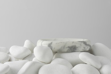 Photo of Presentation for product. Stone podium and white pebbles on light background. Space for text