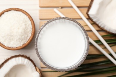 Photo of Glass of delicious vegan milk and coconuts on white wooden table, flat lay