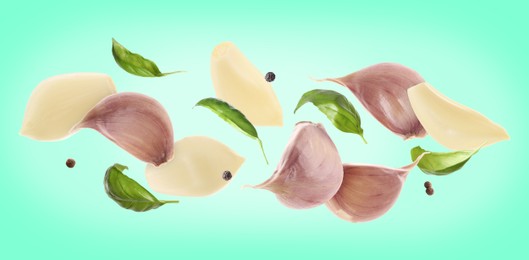 Image of Fresh garlic cloves falling on aquamarine background, banner design