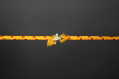 Frayed rope at breaking point on gray background