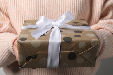 Woman holding gift box with bow as background, closeup