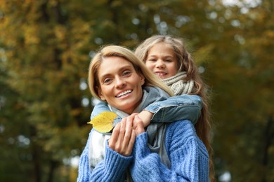Photo of Portrait of happy mother and her daughter with dry leaf in autumn park