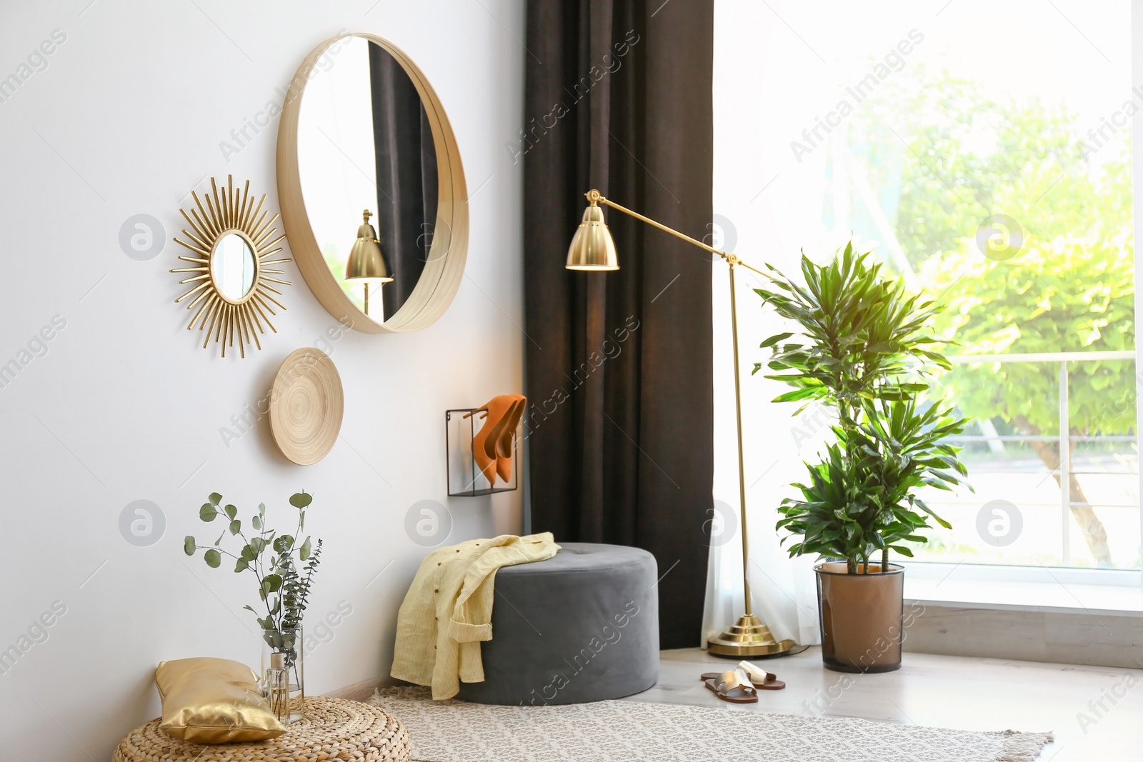 Photo of Hallway interior with big round mirror and ottoman chair near white wall