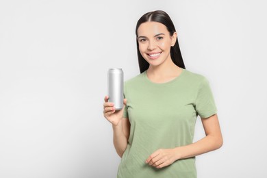 Photo of Beautiful happy woman holding beverage can on light grey background. Space for text