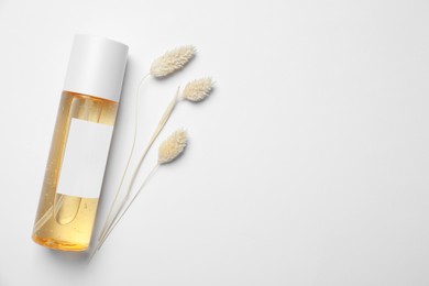 Bottle of cosmetic product and dry decorative spikes on white background, flat lay. Space for text