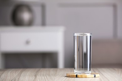 Photo of Glass of clean water on wooden table indoors, space for text