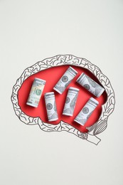 Photo of Rolled dollar banknotes on red background, top view through paper with brain shaped hole and drawing