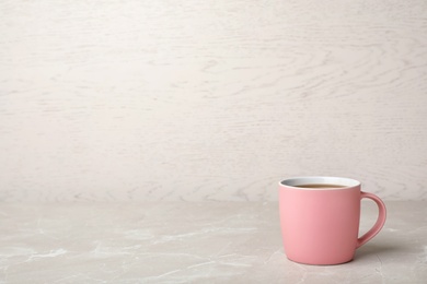Photo of Pink ceramic cup with hot aromatic coffee on table