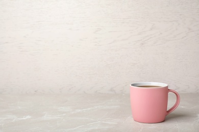 Pink ceramic cup with hot aromatic coffee on table