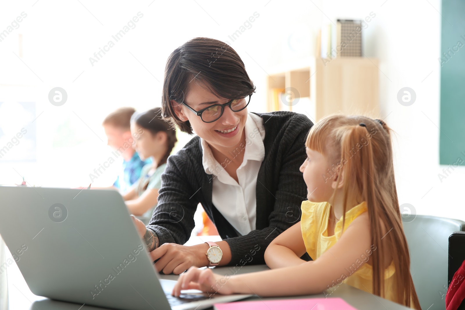 Photo of Female teacher helping child with assignment at school