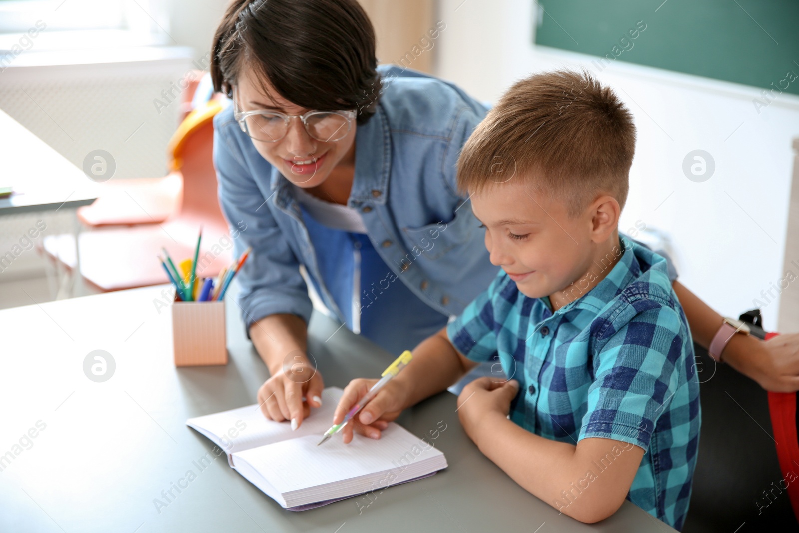 Photo of Female teacher helping child with assignment at school