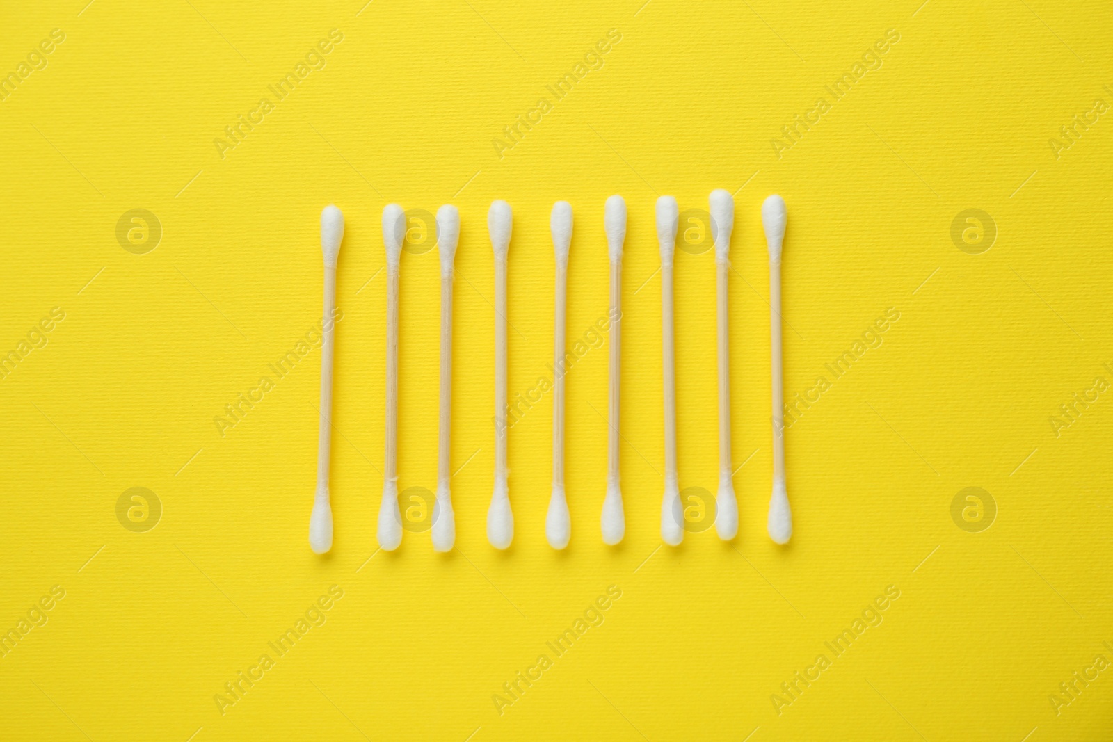 Photo of Many wooden cotton buds on yellow background, flat lay